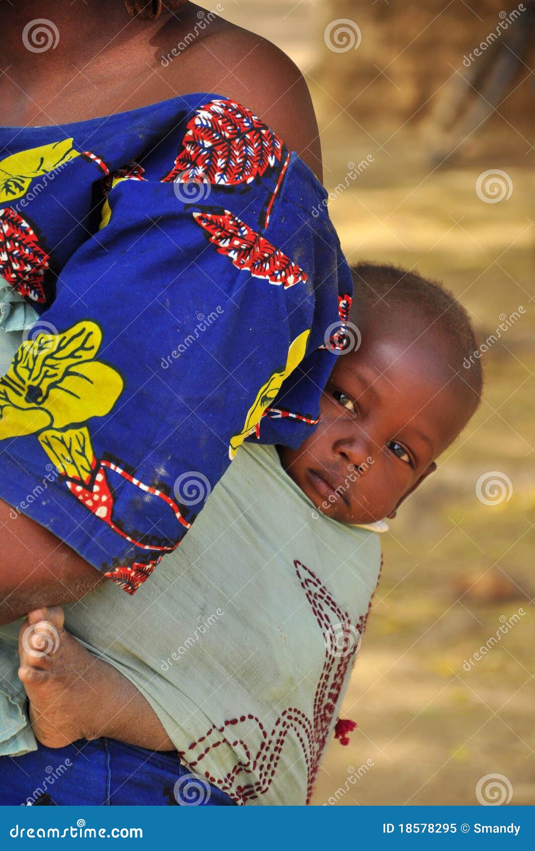 Il bambino africano ha continuato la parte posteriore. Il bambino africano ha trasportato tramite la madre sul modo posteriore e tradizionale nel villaggio Niger, Africa occidentale del hausa,