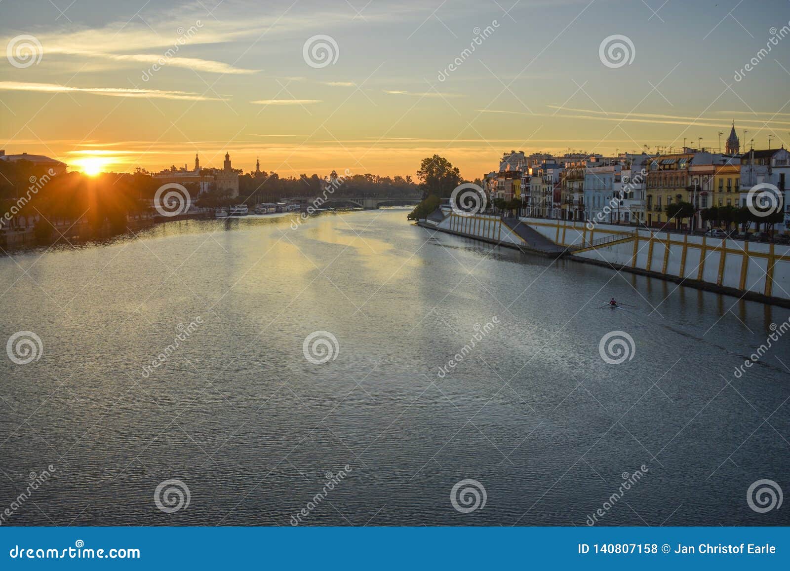 Il fiume Guadalquivir ad alba. Il fiume di Guadalquivir che attraversa Siviglia in Spagna del sud, essendo trasformando dalla luce del sol levante con le case che allineano il lungofiume dal lato lontano e un ponte nei precedenti