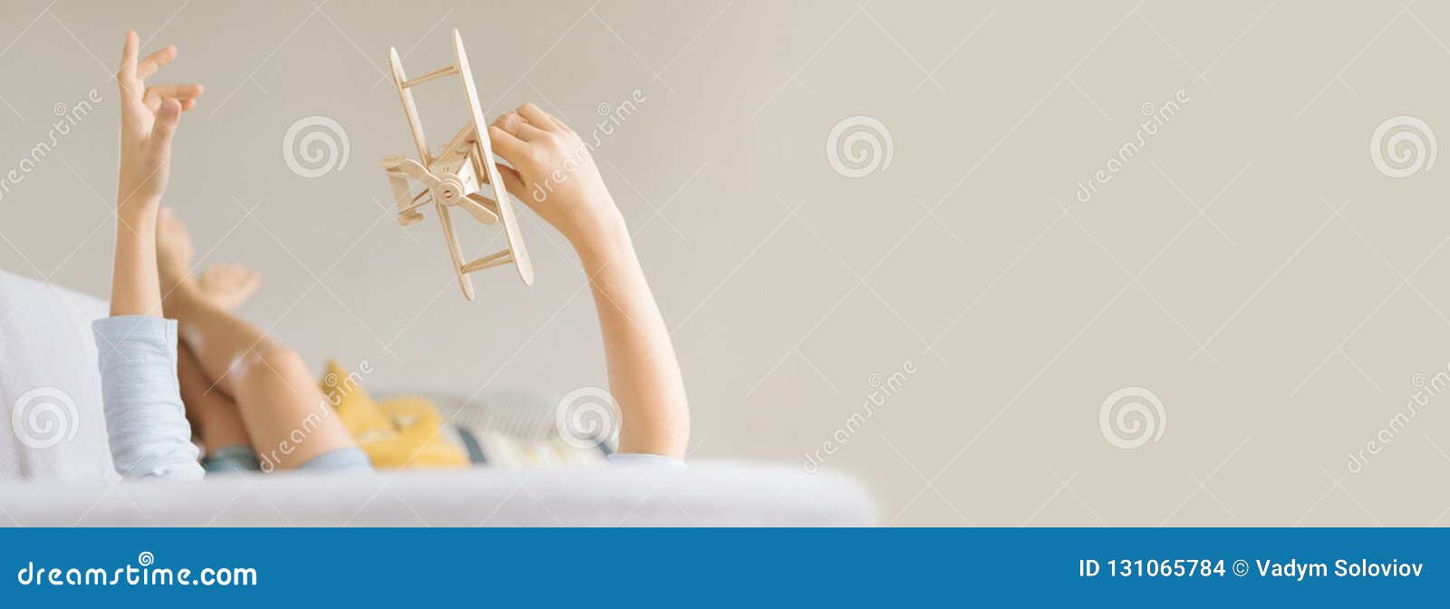 Il ragazzo si trova sul sofà e gioca un aereo del giocattolo Immagine con un più grande spazio della copia