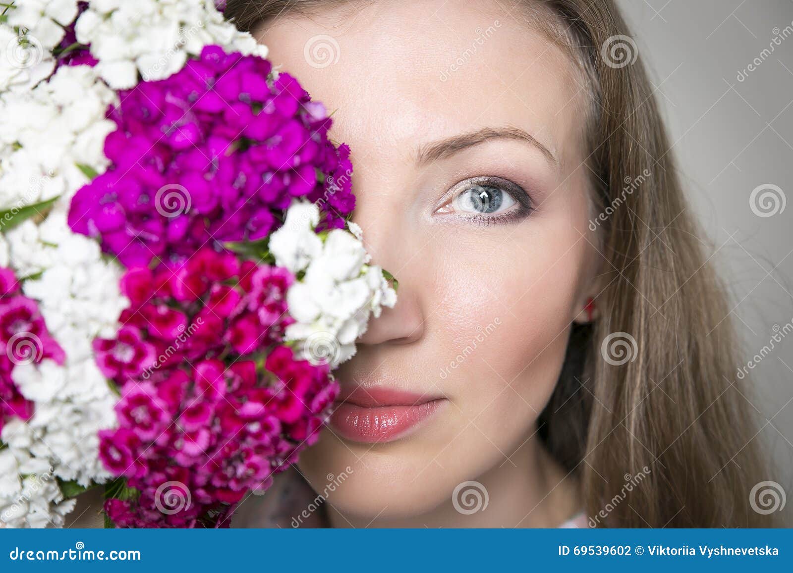 Il ritratto del primo piano di giovane bella donna alla moda con la molla splendida fiorisce I fiori riguardano la metà del front