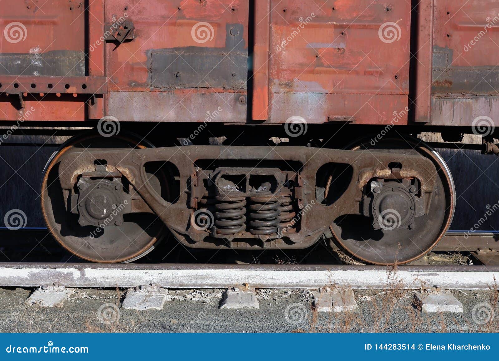 Il vagone di vecchio treno merci arrugginito sta sulle rotaie. L'automobile di vecchio treno merci arrugginito sta sulle rotaie; la sola parte dell'automobile nella priorità alta può vedere la vegetazione asciutta invasa