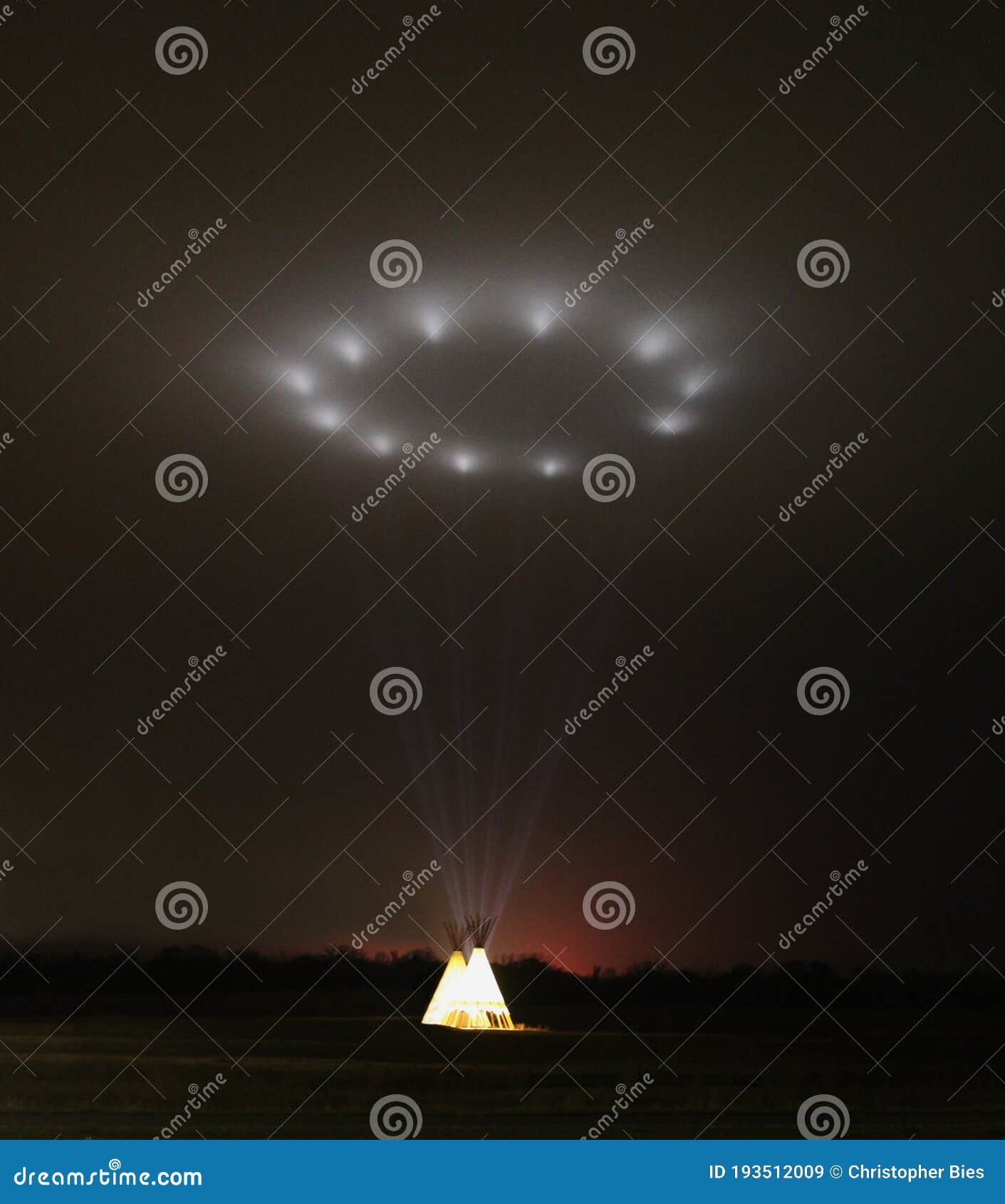 illuminated tipi, teepee, at night projecting light into the sky