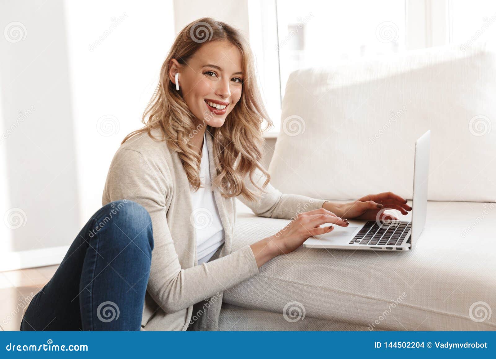 Woman sitting on sofa, using laptop computer, side view 