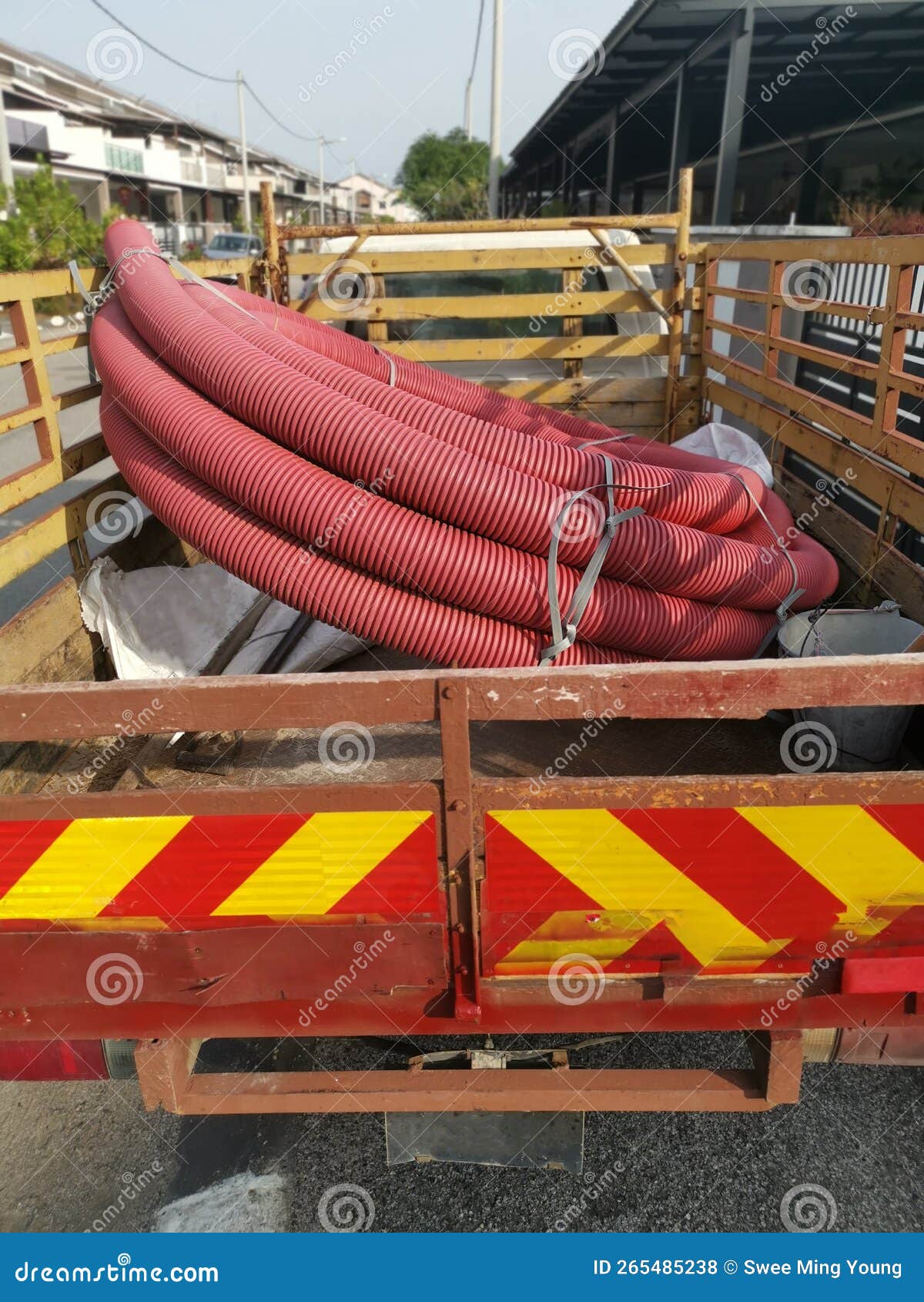 Bundle of Vermilion Red PVC Plastic Industrial Pipe Hose at the Back of