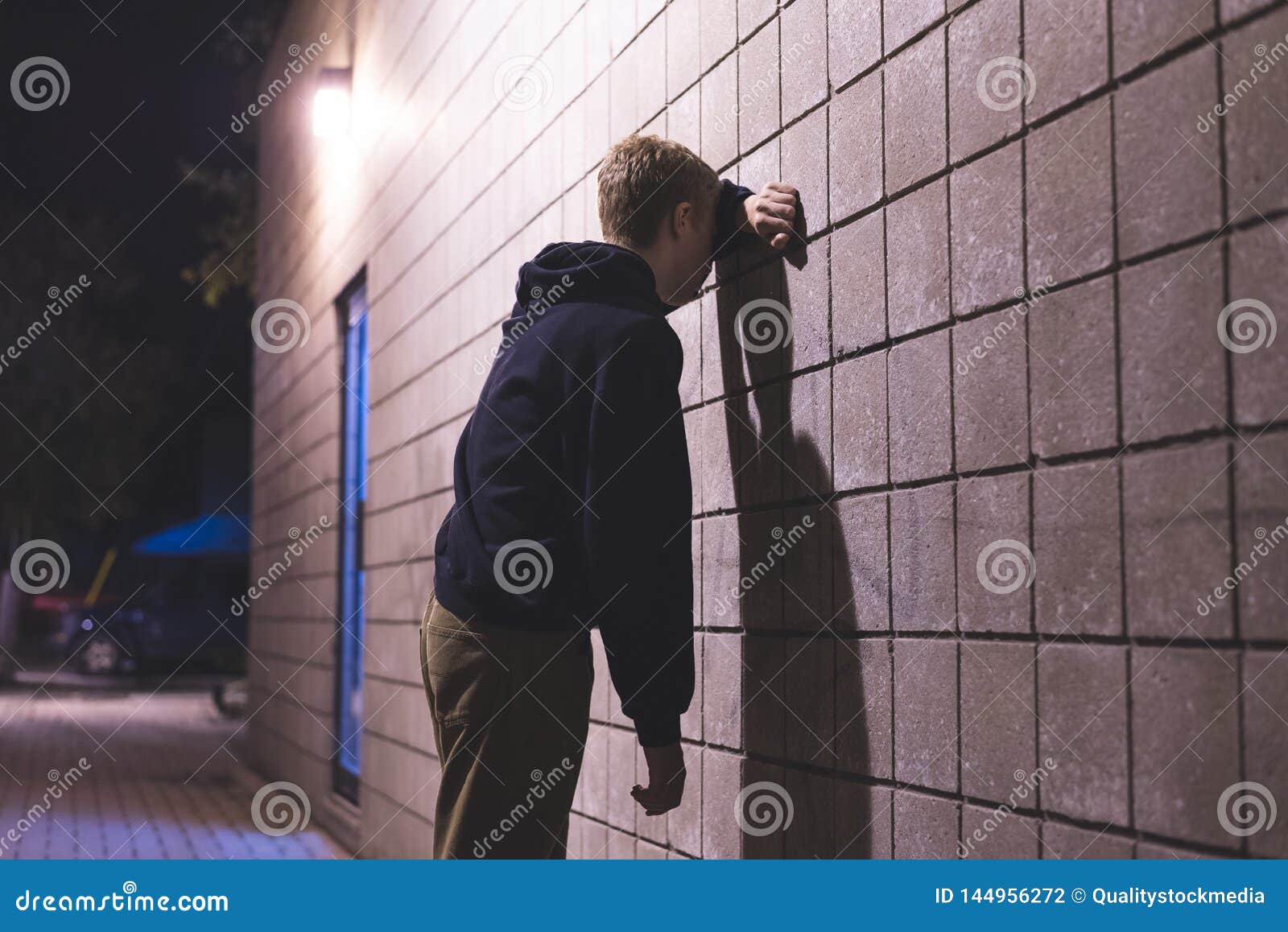 upset teenager standing in an alleyway.