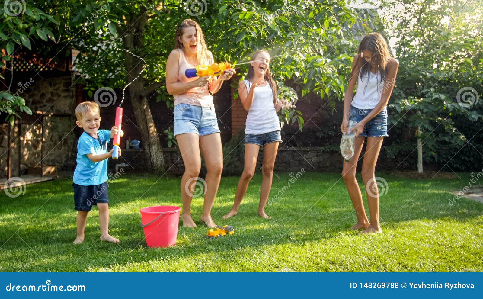 Photo Of Happy Children Having Water Gun Fight At House Backyard Garden