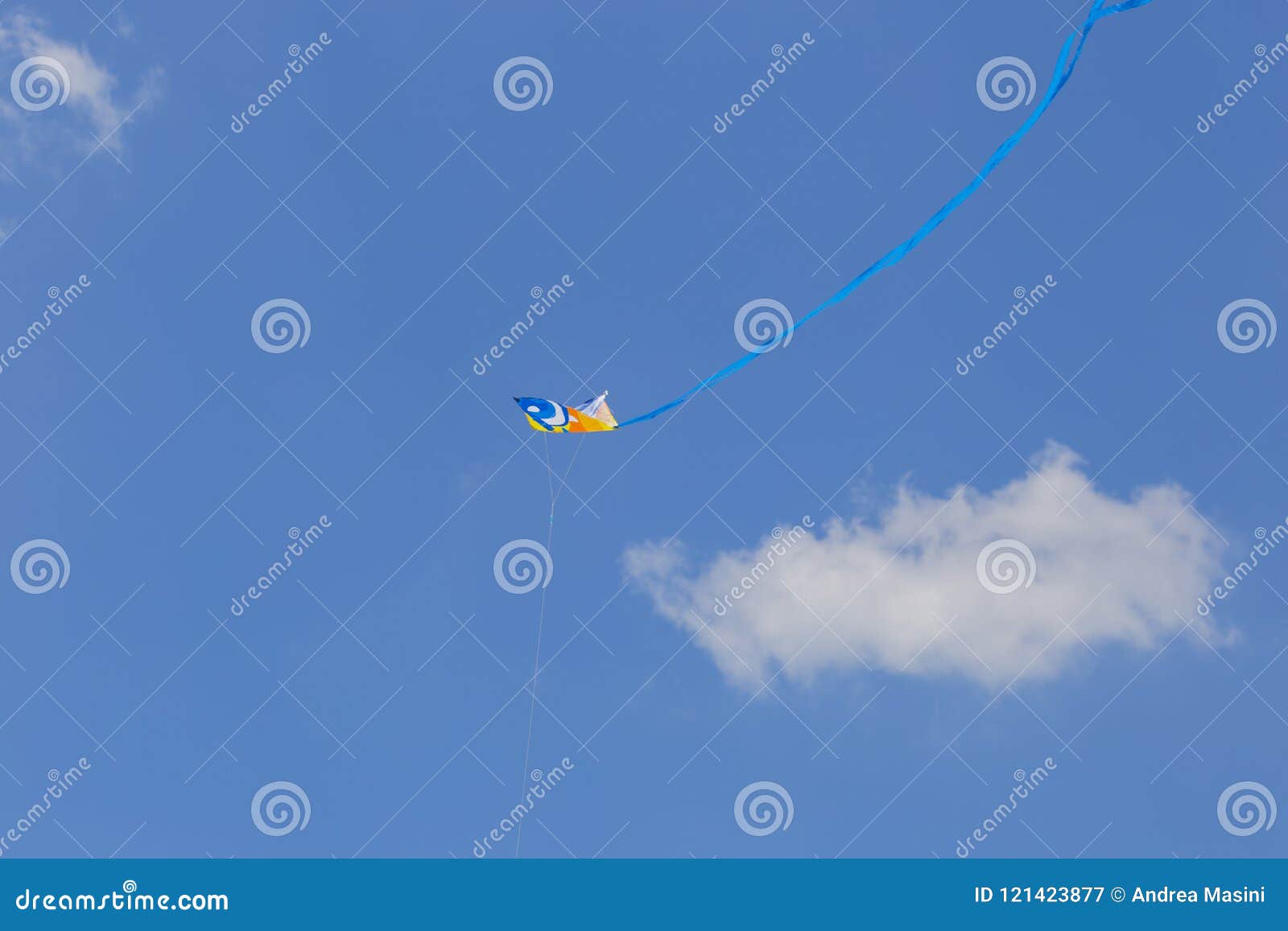 image of a kite flying in the blue sky with a long blue ribbon