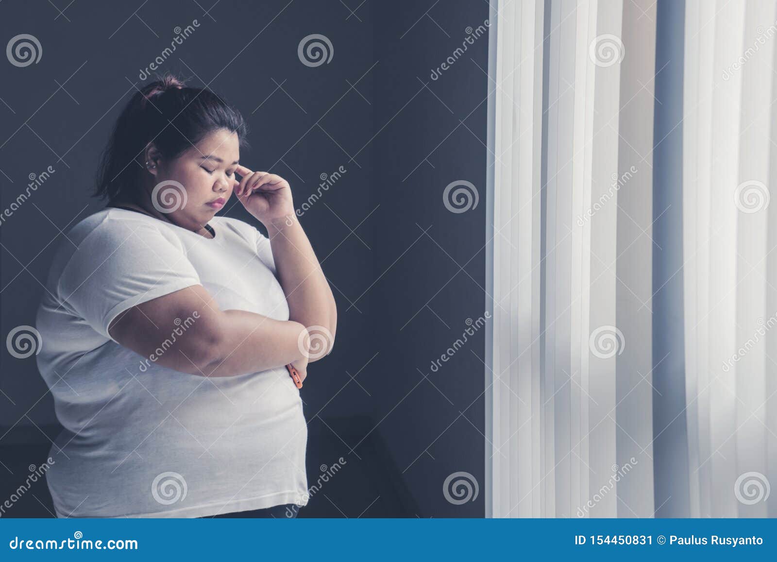obese woman thinking something near the window
