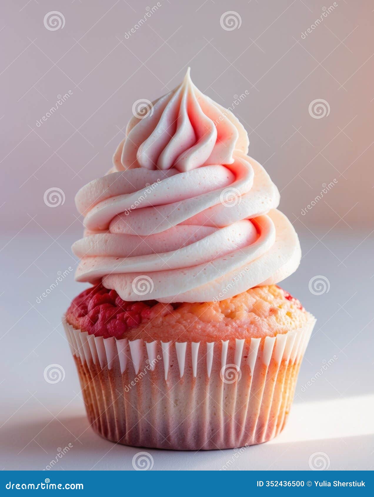 an image of a strawberry cupcake topped with pastel whipped cream frosting