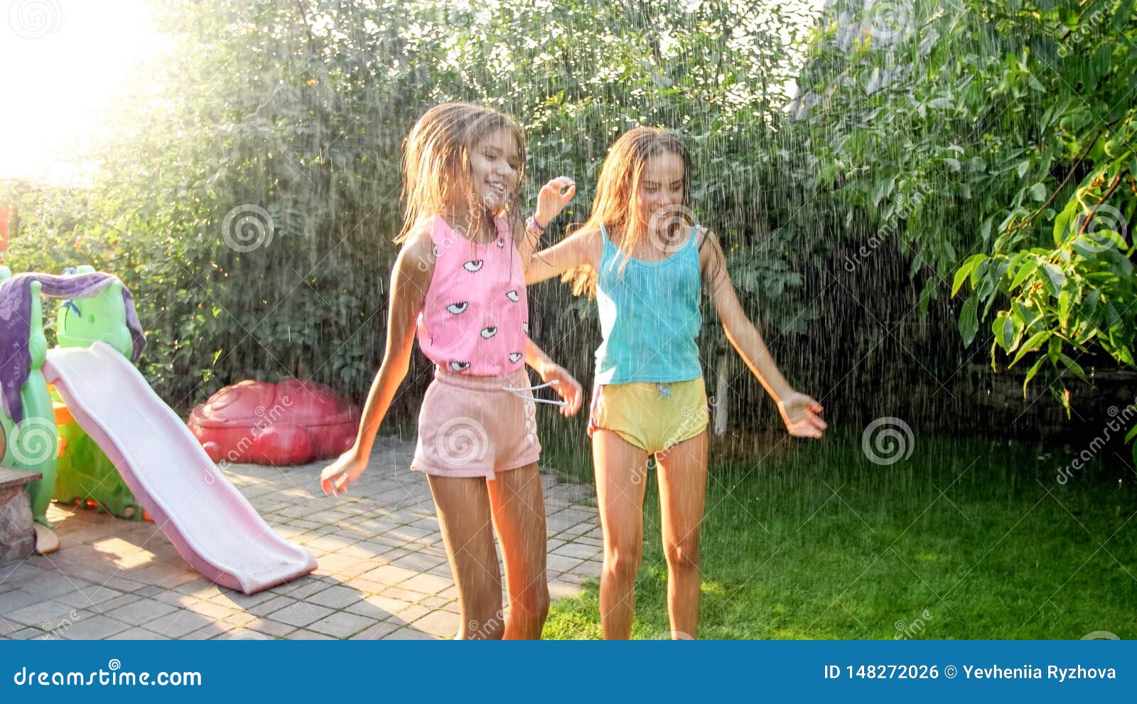 Image Of Two Happy Laughing Teenage Girls Jumping And Dancing Under Warm Summer Rain At House