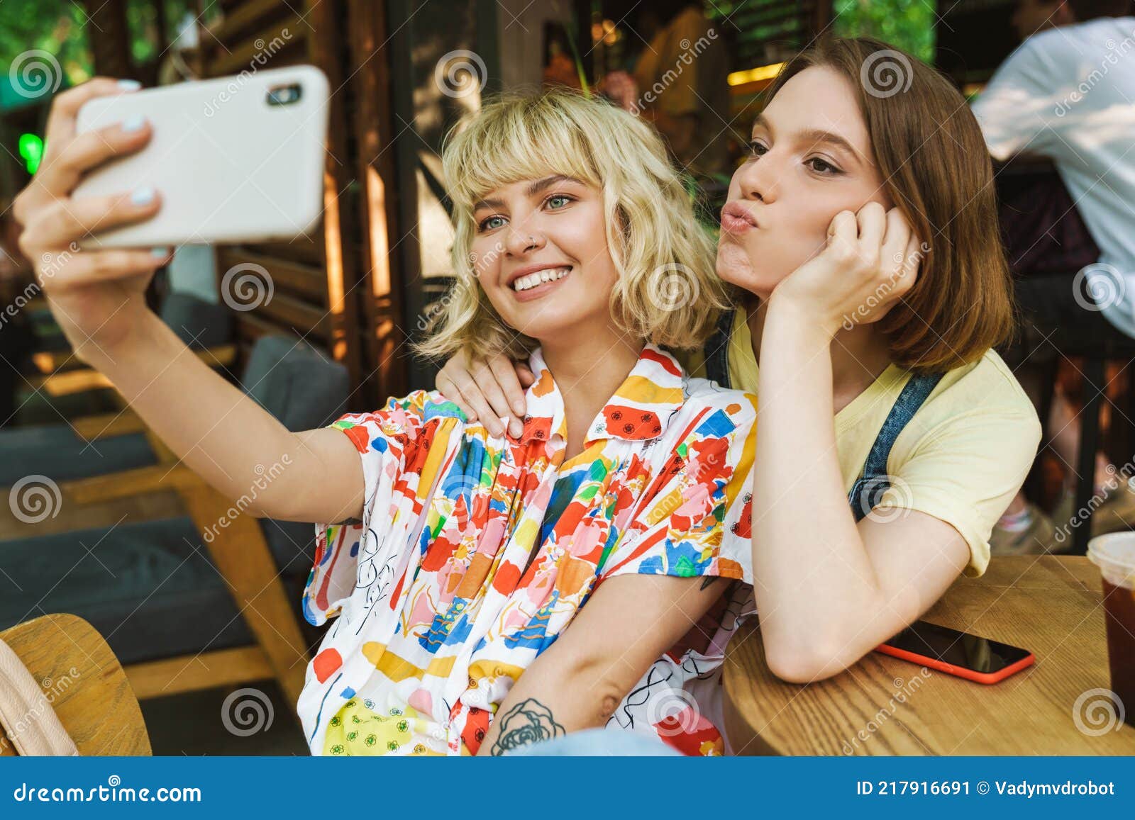 Image of Two Women Taking Selfie on Cellphone while Sitting in Cafe ...