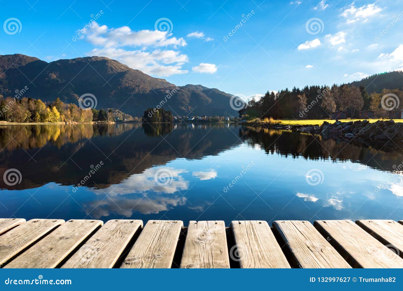 wood texture and beautiful autumn landscape background with colorful trees, mountains, clouds in blue sky and lake reflection