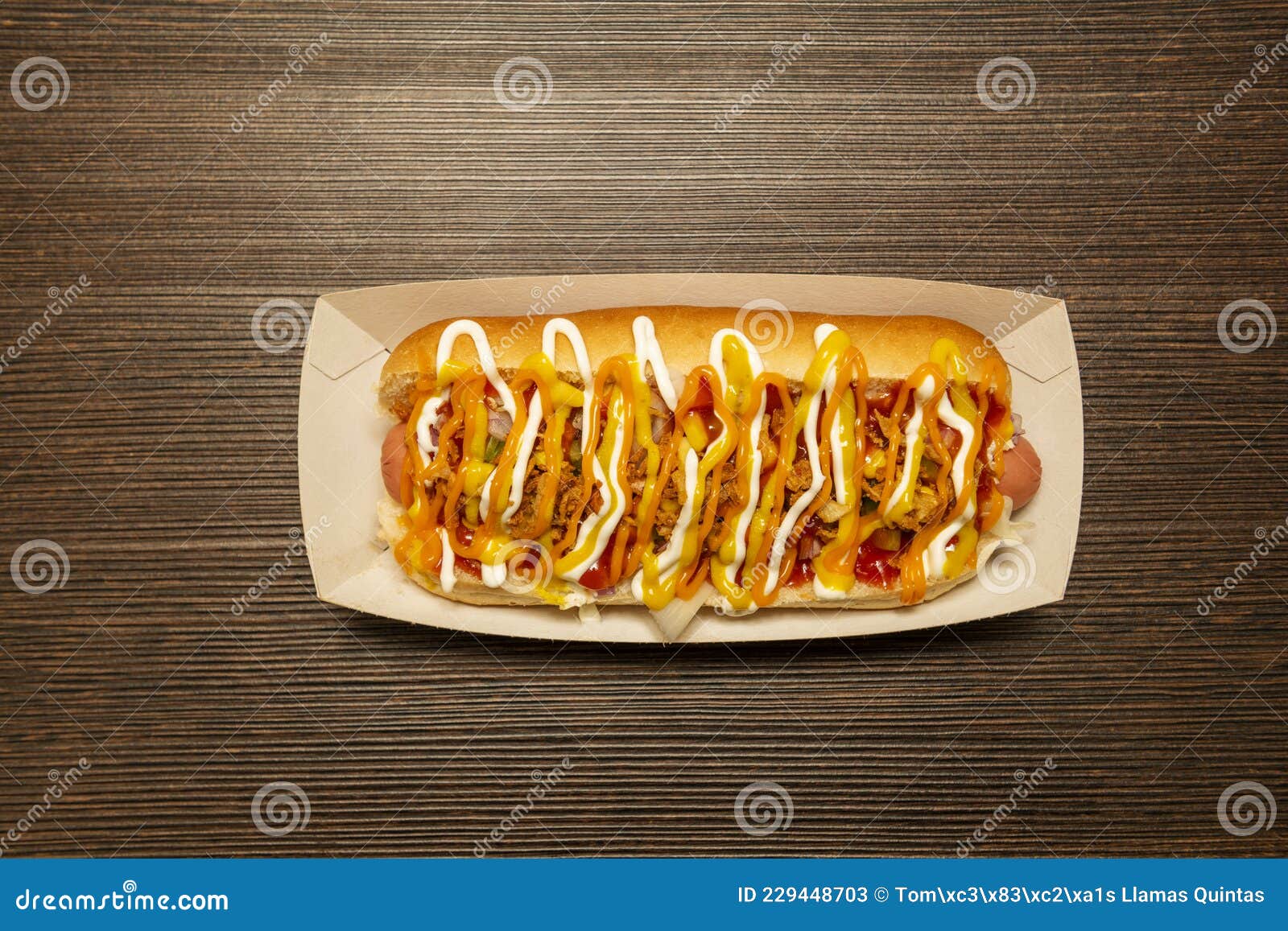 top view image of hot dog with sausage covered by lots of sauces