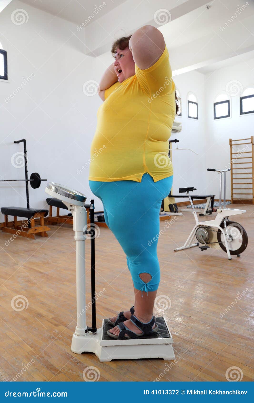 impressed overweight woman on scales in gym