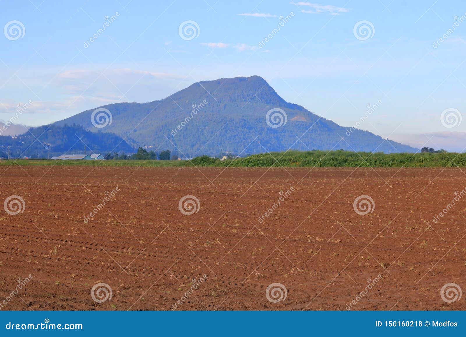 Inactieve Vulkaan en Landbouwgrond. Een oude inactieve vulkaan overziet eerste landbouwlandbouwgrond die voor het zaaien klaar is