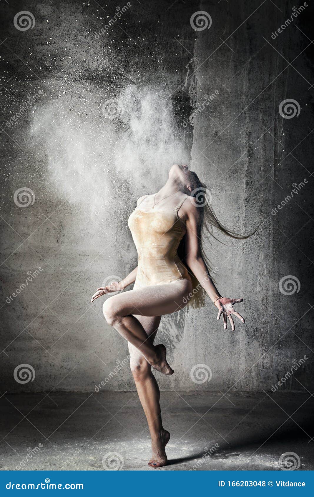 incredibly beautiful pose of a dancer with flying flour on a gray background.