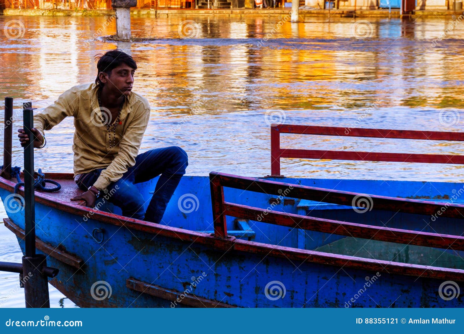 indian boatsman sitting on his boat editorial photo