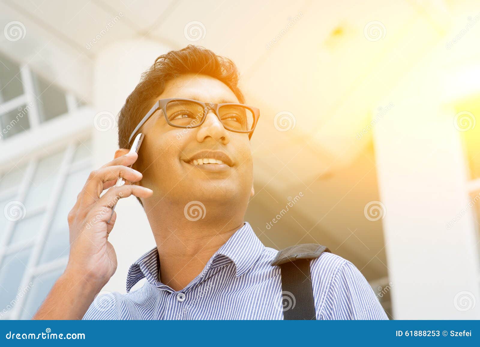 Indian business people talking on smartphone. Indian businessman talking on phone in front modern office building. Urban view with sunlight.