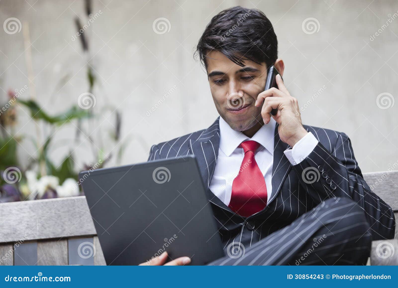 An Indian Businessman Using Tablet PC while Communicating on Cell Phone