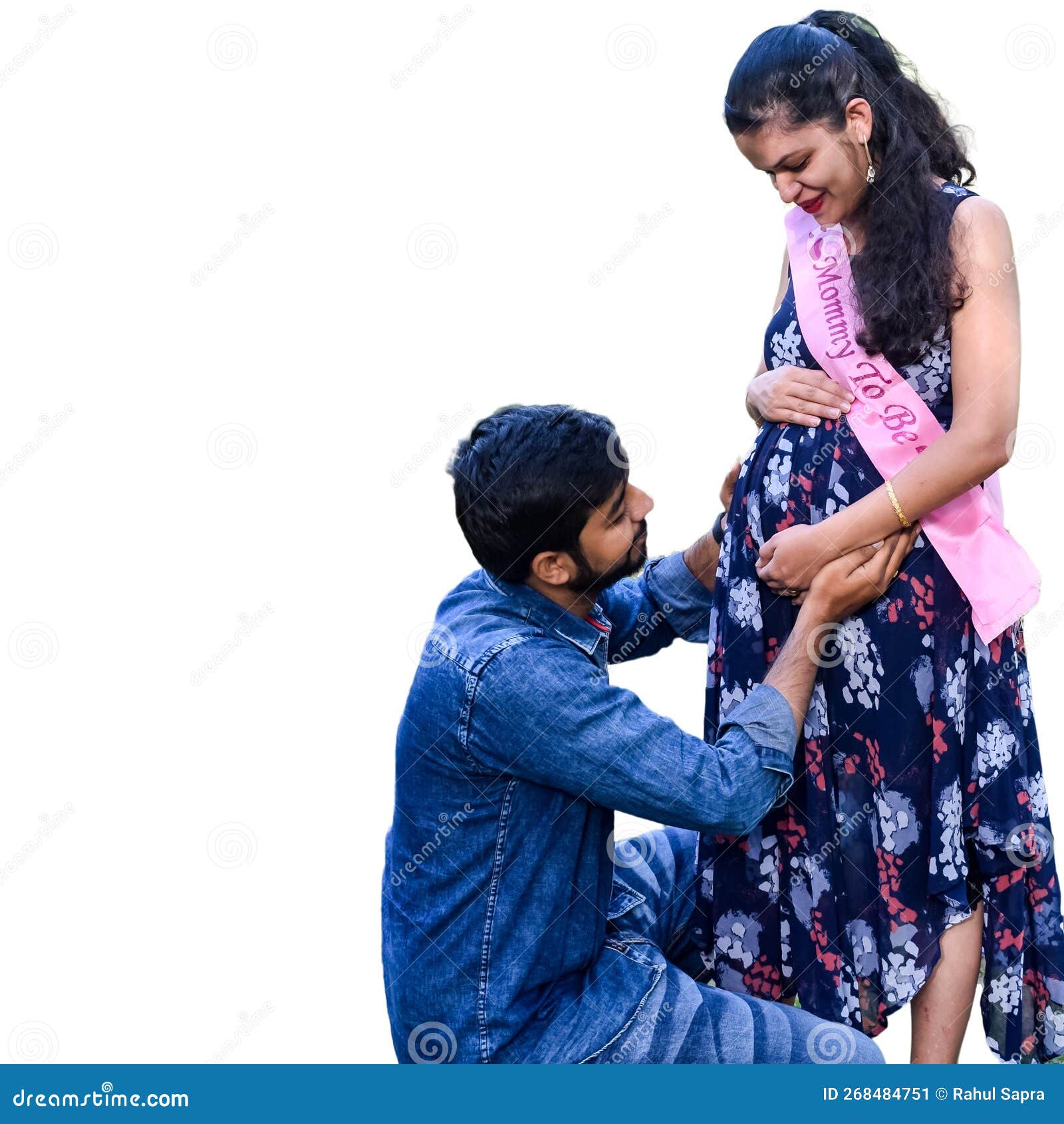 indian couple posing maternity baby shoot white plain background lawn green grass woman falunting her 268484751