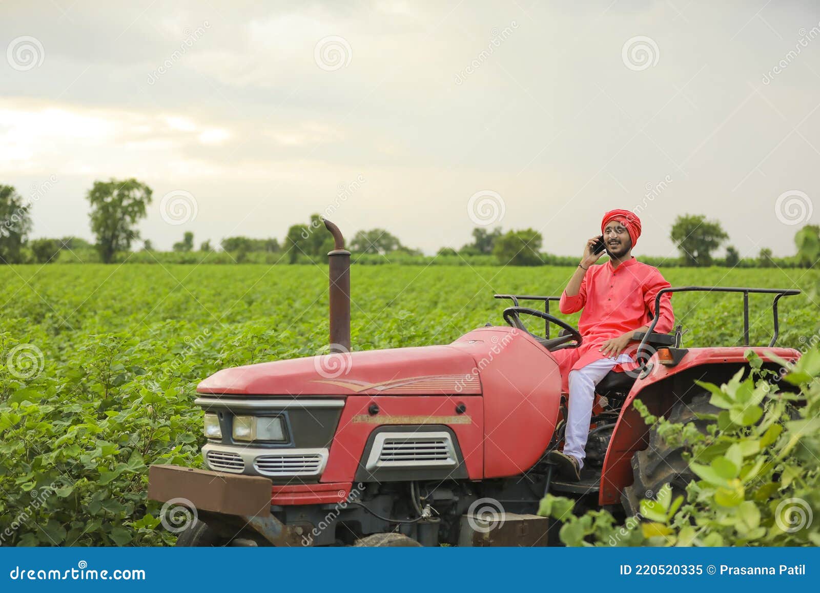 Indian Farmer Working with Tractor and Using Smartphone at Field Stock