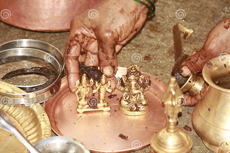 An Indian Hindu Woman Cleaning Idols and Household Equipments Using