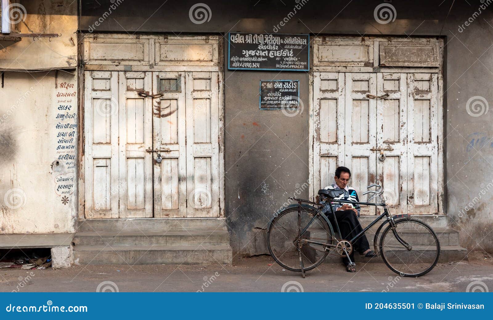 An Indian Man Sitting Alone with His Bicycle Editorial Photo