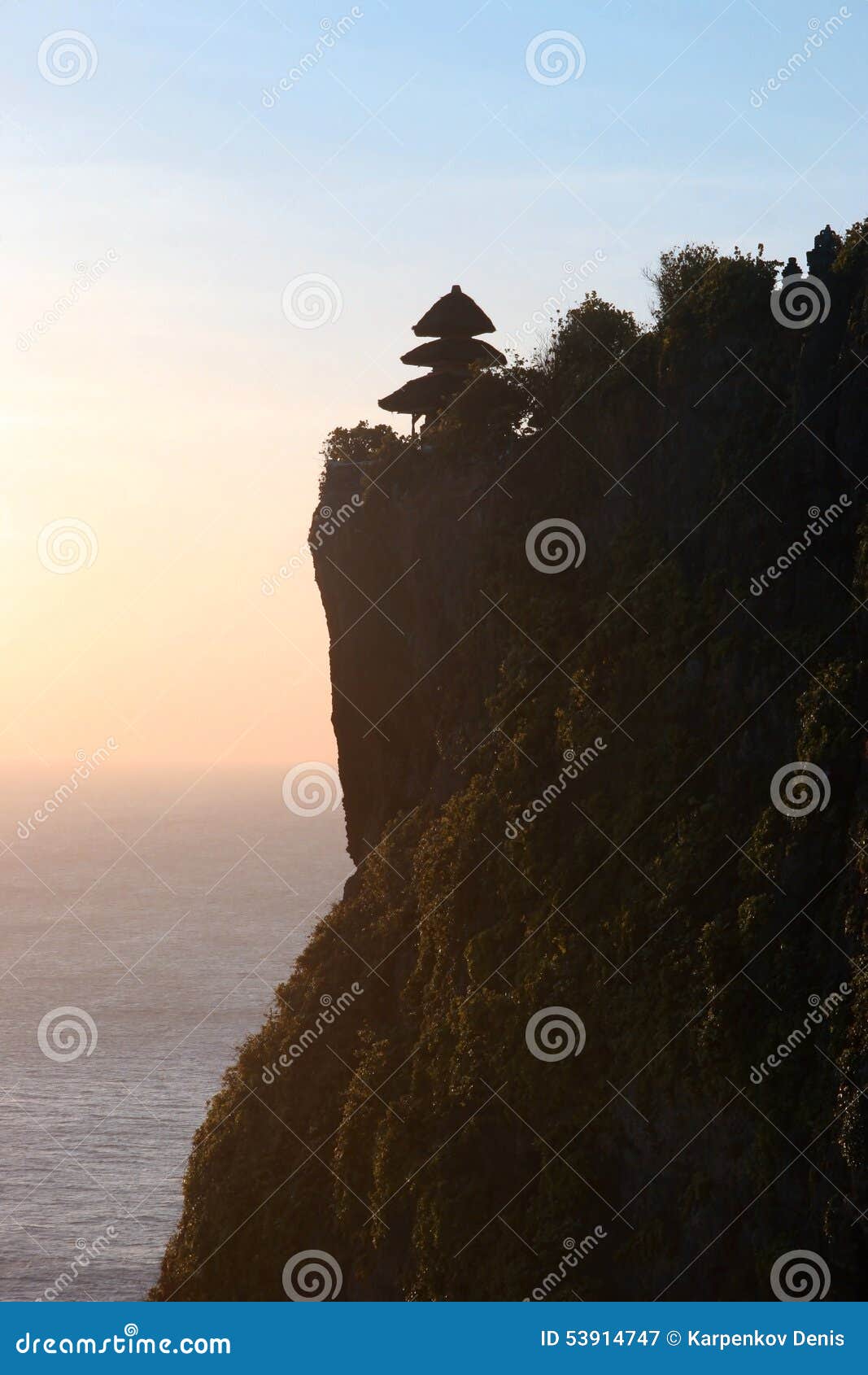 Indonesian temple on the mountain at the sunset over the ocean