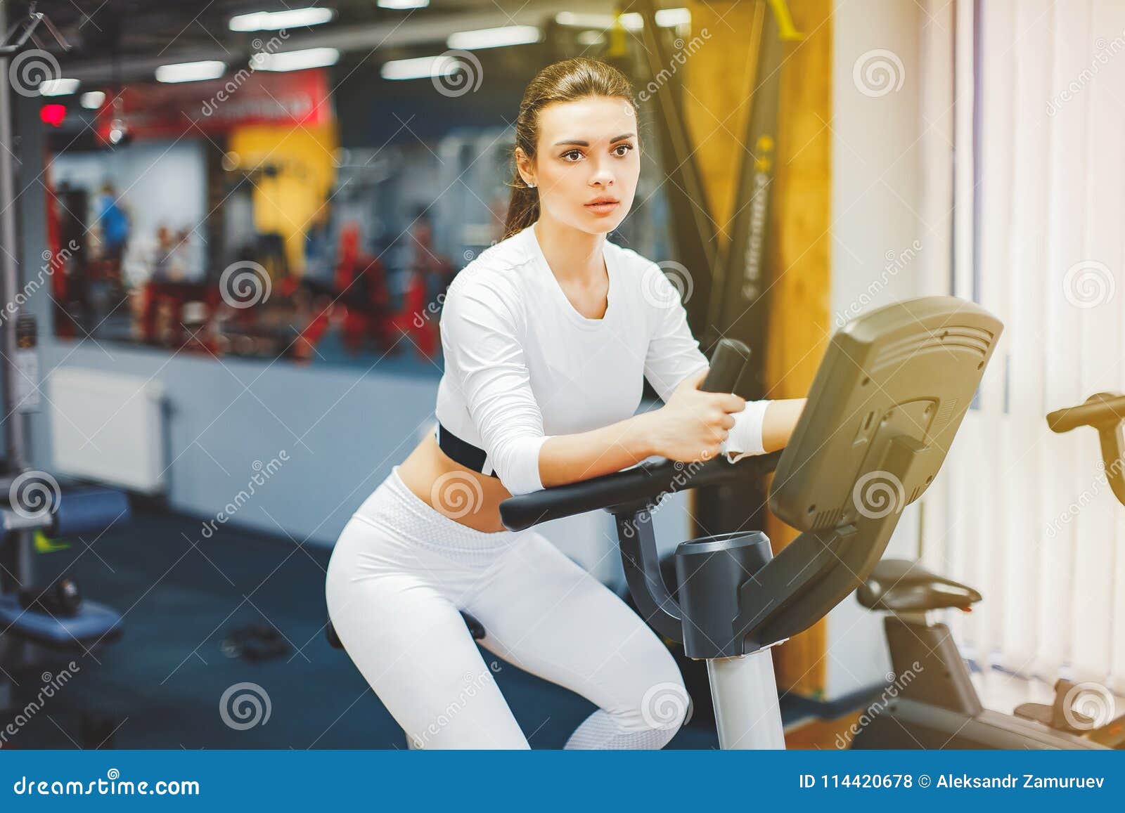 Woman riding an exercise bike in gym. Indoor cycling 