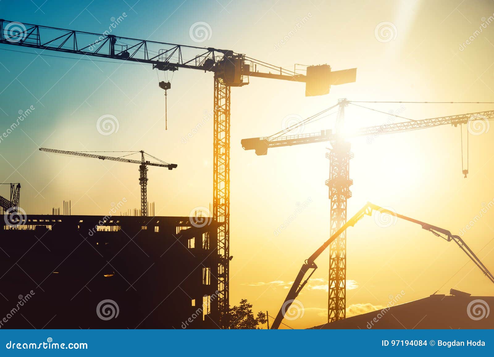 industrial heavy duty construction site with tower cranes and building silhouettes
