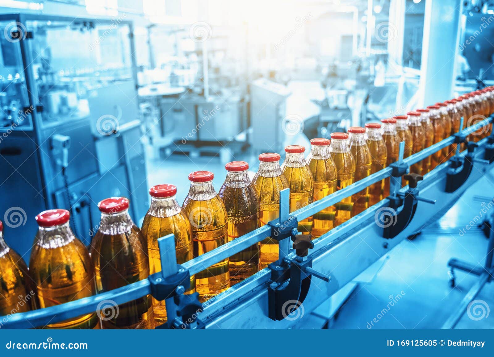 industrial interior of natural juice plant production in blue color. conveyor belt, filled bottles on beverage factory