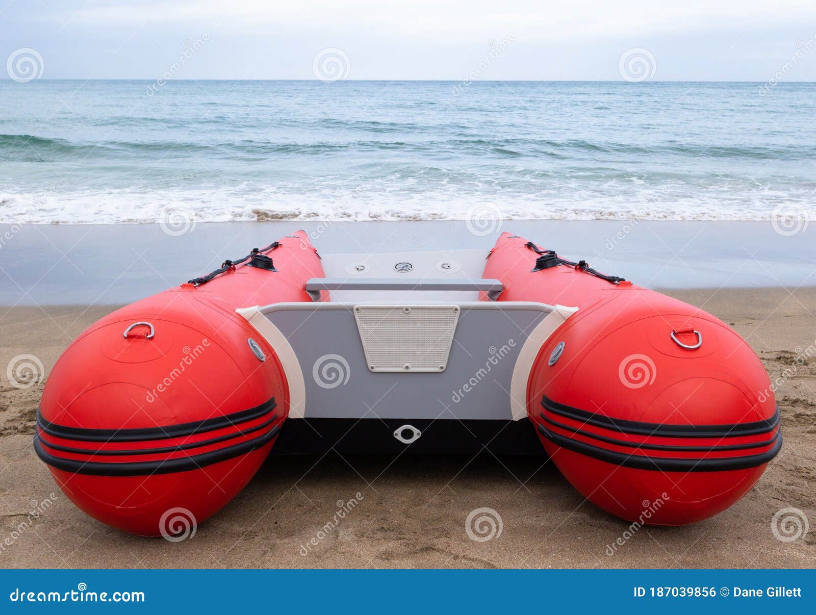 Rigid hull inflatable boat with outboard motor in the shore beaten by the  waves. Used to fish at sea Stock Photo by wirestock