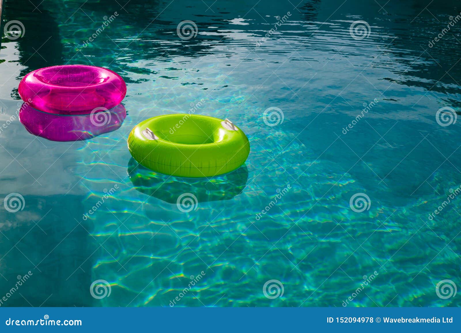 Inflatable Tubes Floating in a Swimming Pool in Backyard Stock Photo