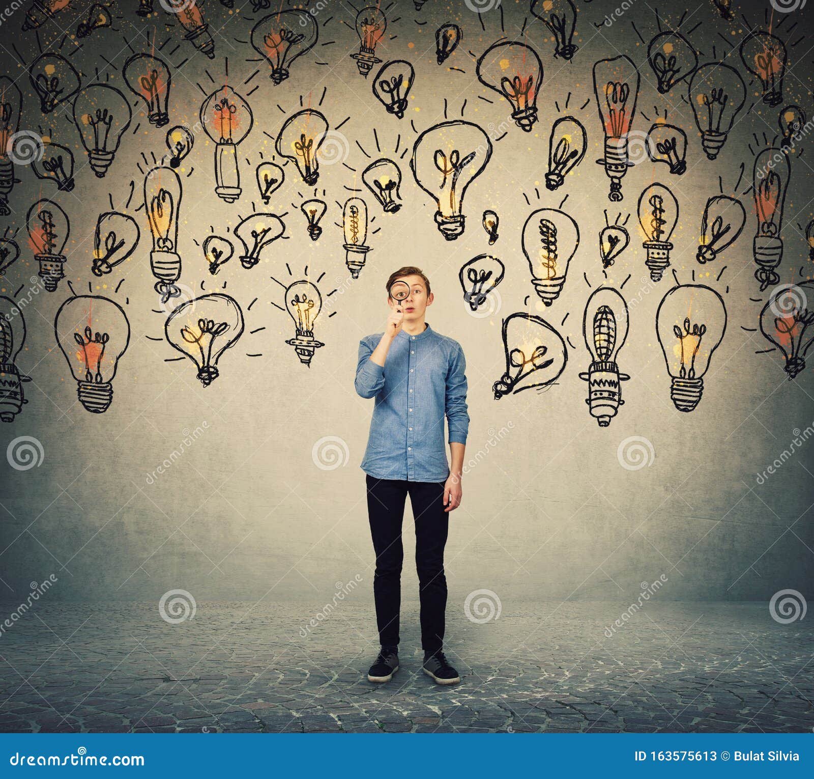 ingenious teenage boy seeking for brilliant ideas as looks curious through the magnifying glass. student boy try to find solutions