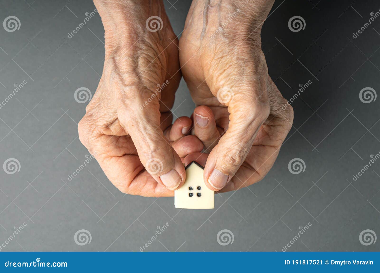 inheritance concept. elderly woman hands give a little toy house.