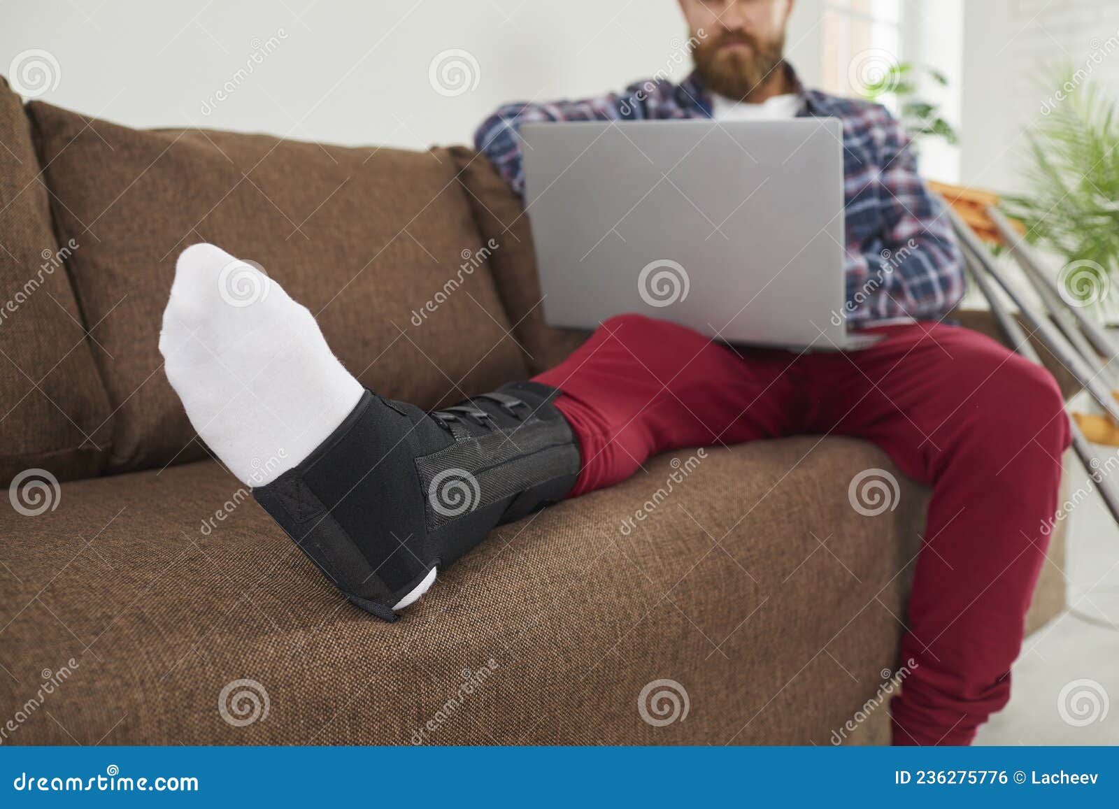 injured man with broken leg work on laptop at home