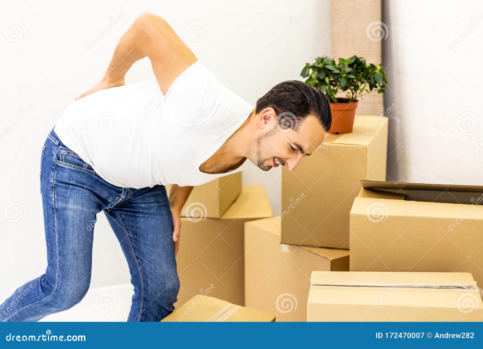 Man Suffering from Cramp in Back while Stacking Boxes, Preparing for Relocation. Stock Image