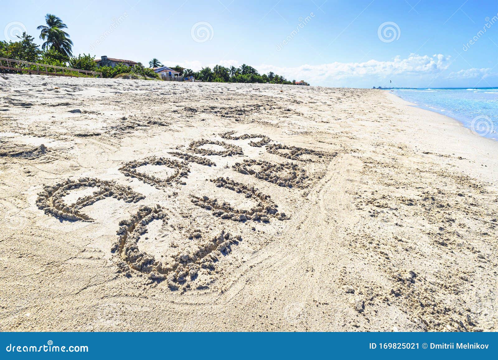 inscription adios cuba on the sandy beach and sea water. translated from spanish goodbye cuba.