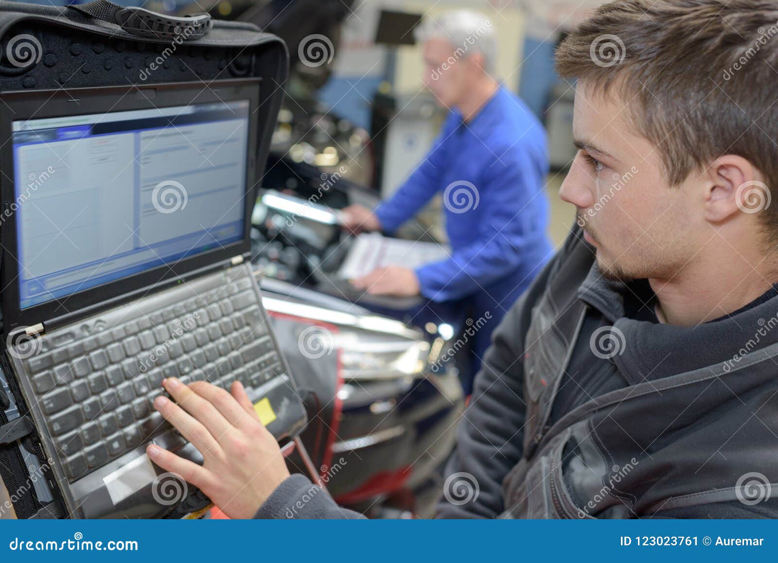 Insegnante ed apprendista del meccanico che eseguono le prove all'auto della scuola del meccanico