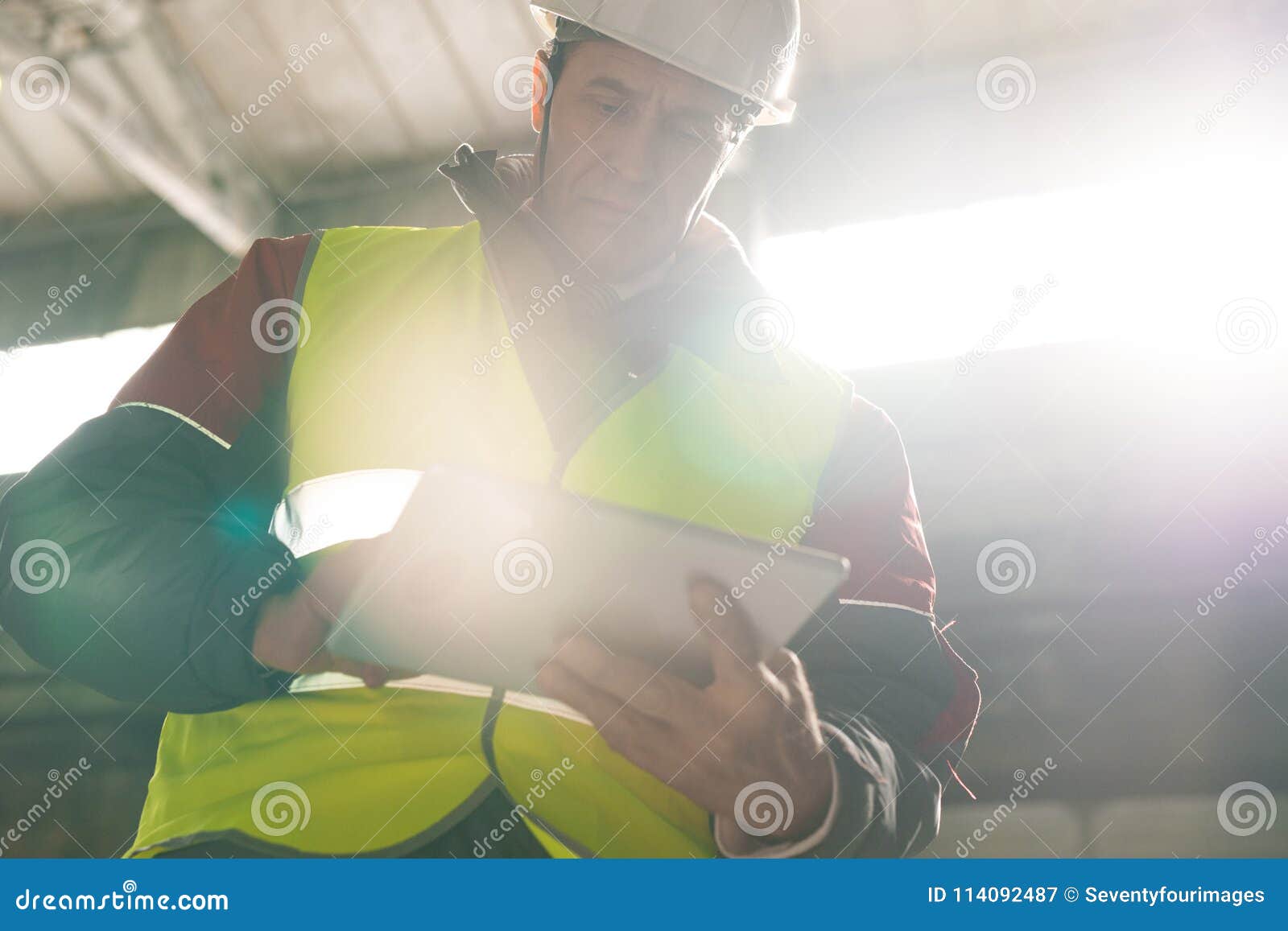 Inspecteur du travail mûr. Portrait d'angle faible de masque de port d'ingénieur mûr utilisant le comprimé numérique dans l'atelier de l'ensemble industriel moderne, l'espace de copie