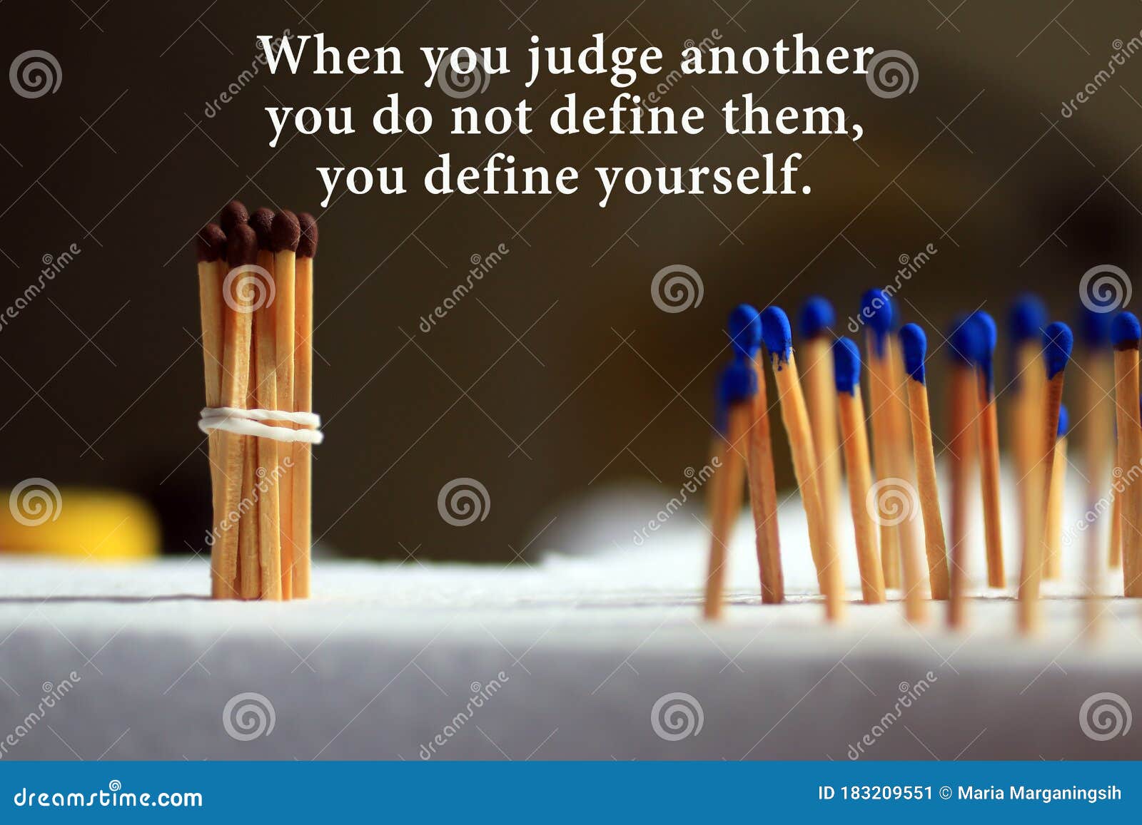 inspirational quote - when you judge another, you do not define them, you define yourself. with background of colorful matches.