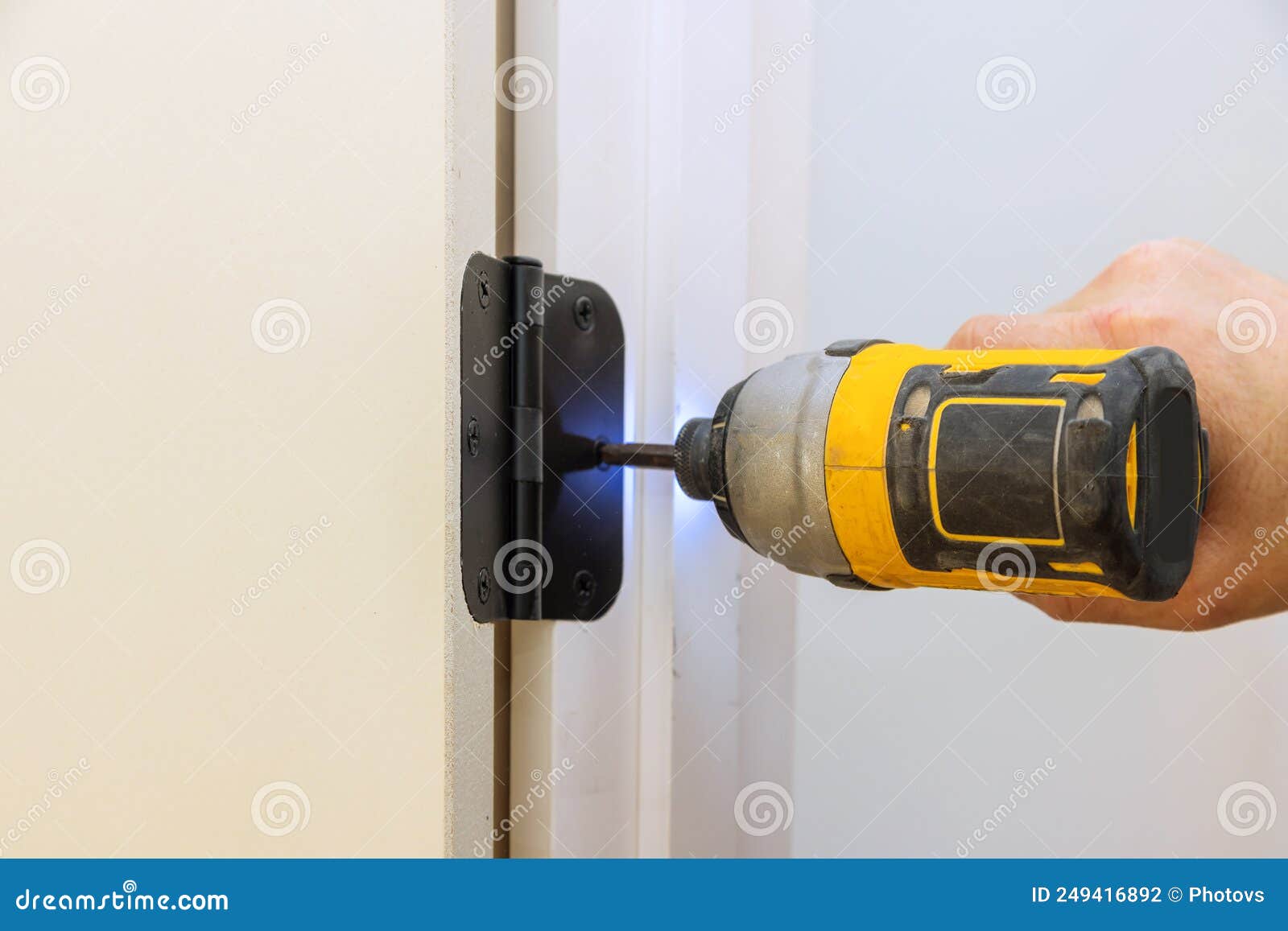 Installing the Door Hinge on the Door Frame Using a Screwdriver a Home