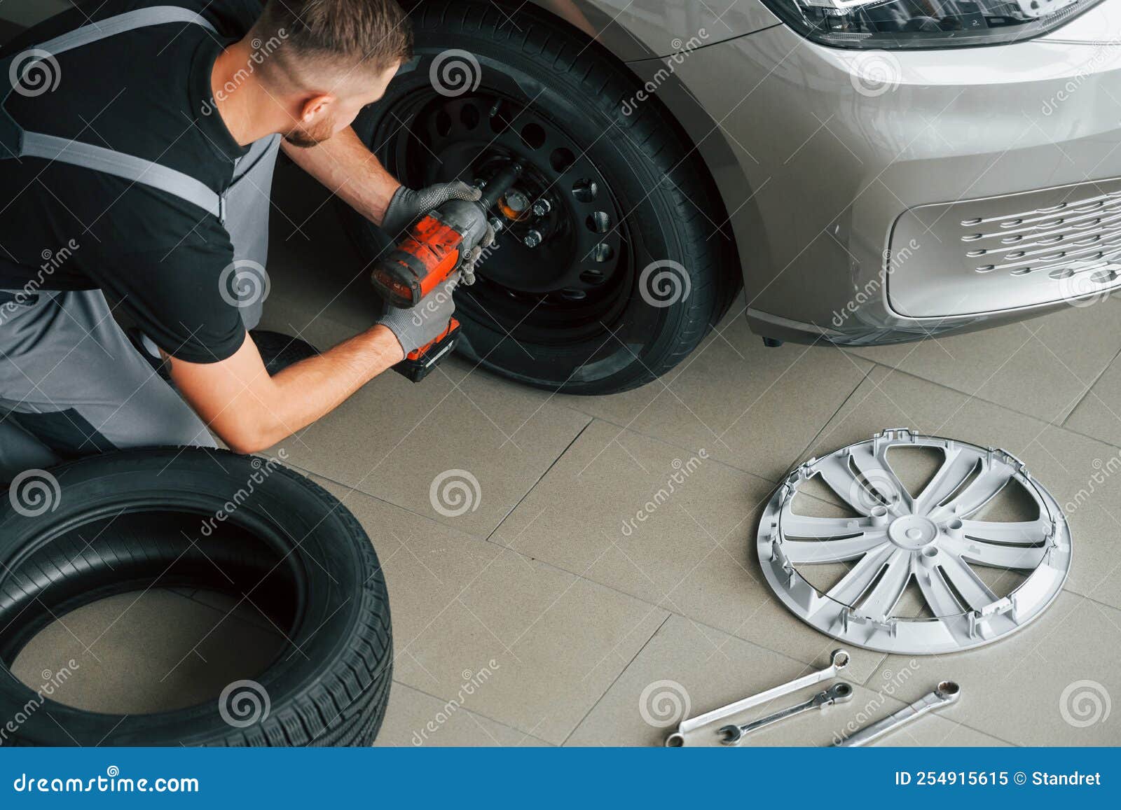 Installing New Tire. Man in Uniform is Working in the Autosalon at