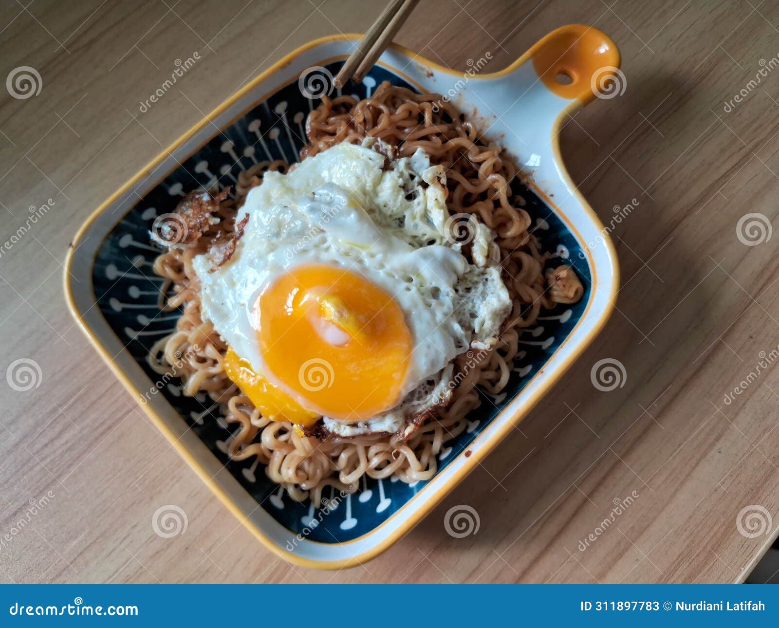instantly fried noddle with a fried egg with wooden background