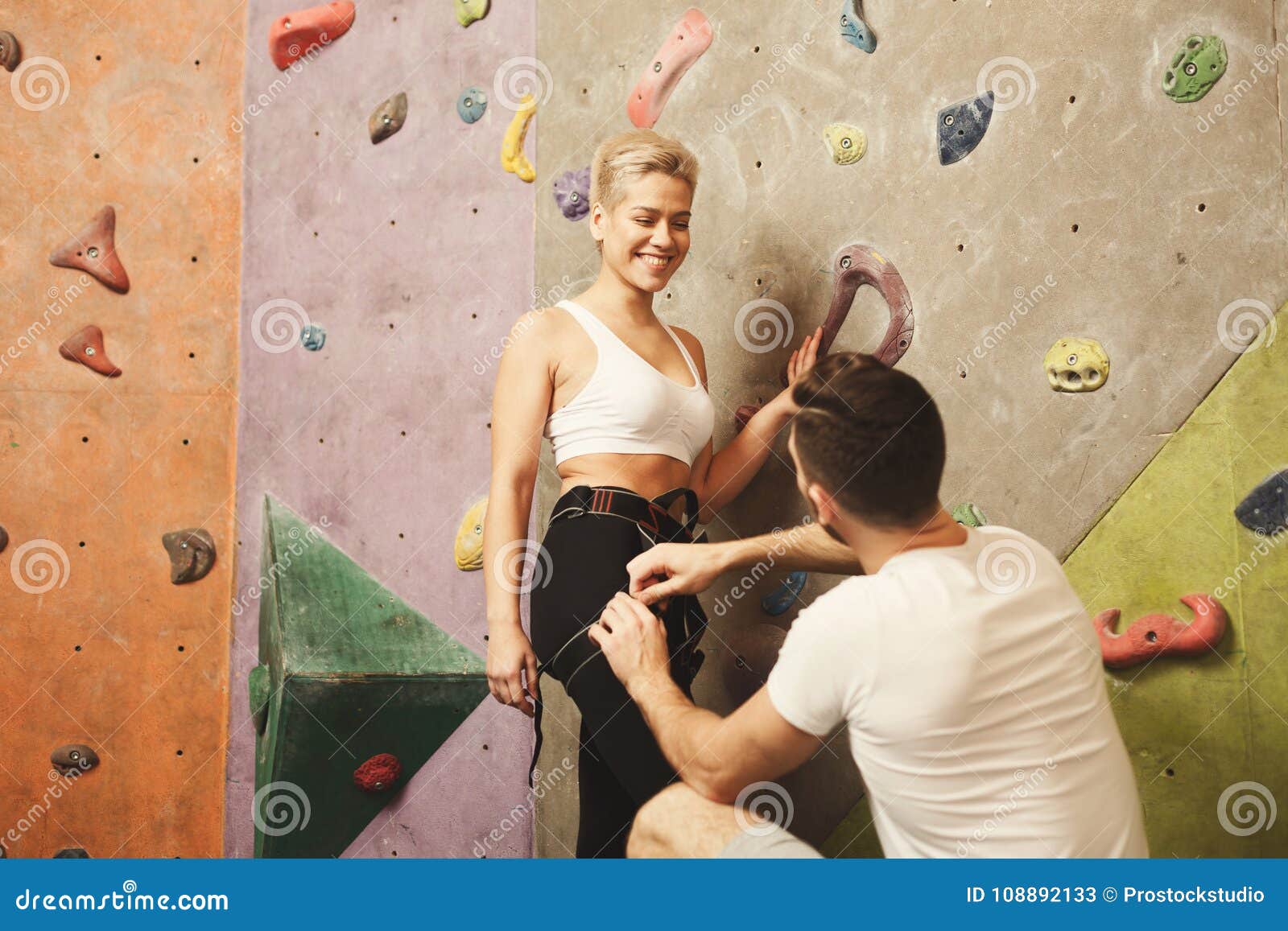 Instructeur die jonge vrouw voor het beklimmen voorbereiden. De mannelijke bus het bevestigen kabel in maakt vast Instructeur die jonge klimmer voor extreme sport opleiding voorbereiden Veiligheid en actief levensstijlconcept