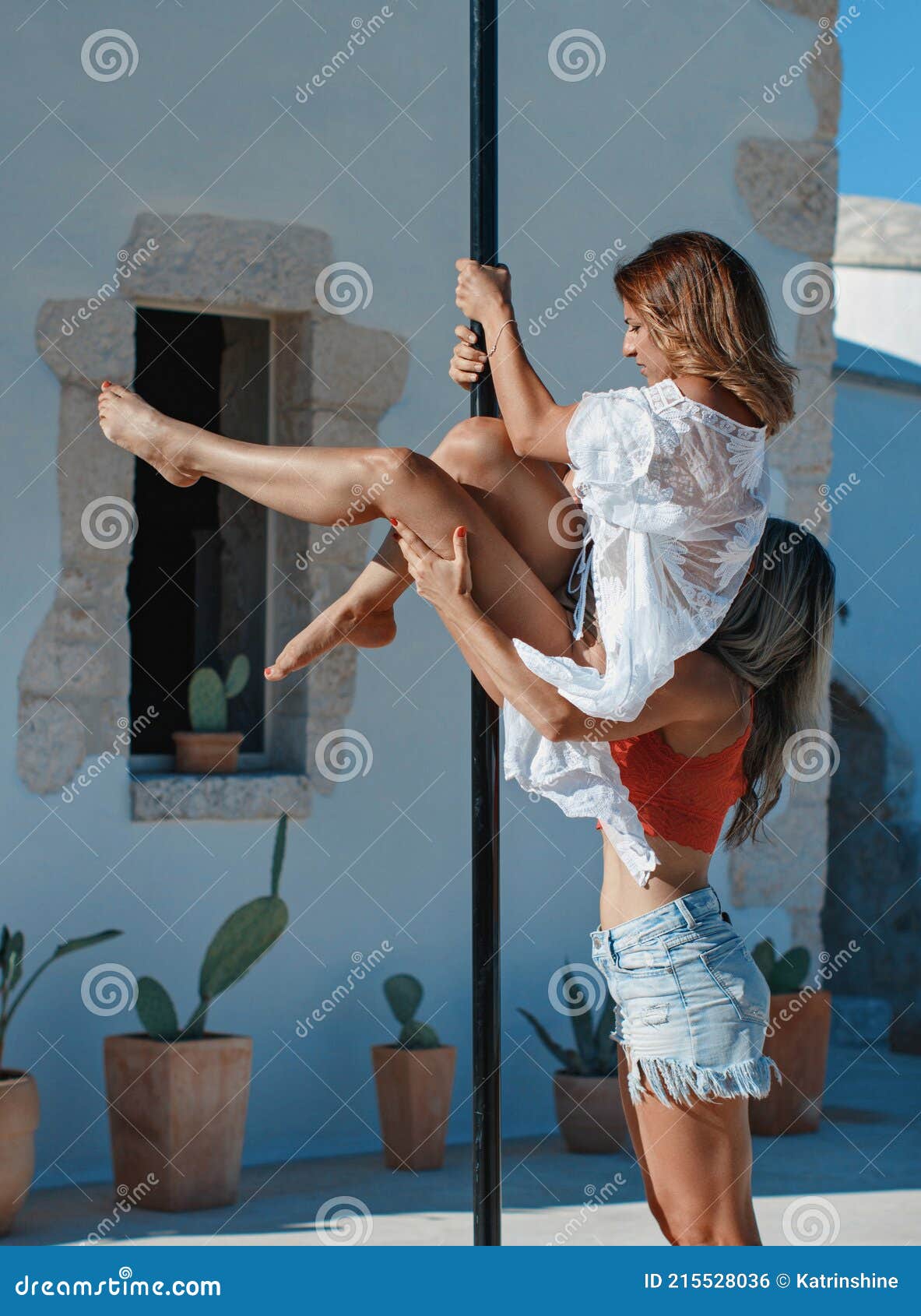 instructor helping young pole dancer to take a pose on a portable platform