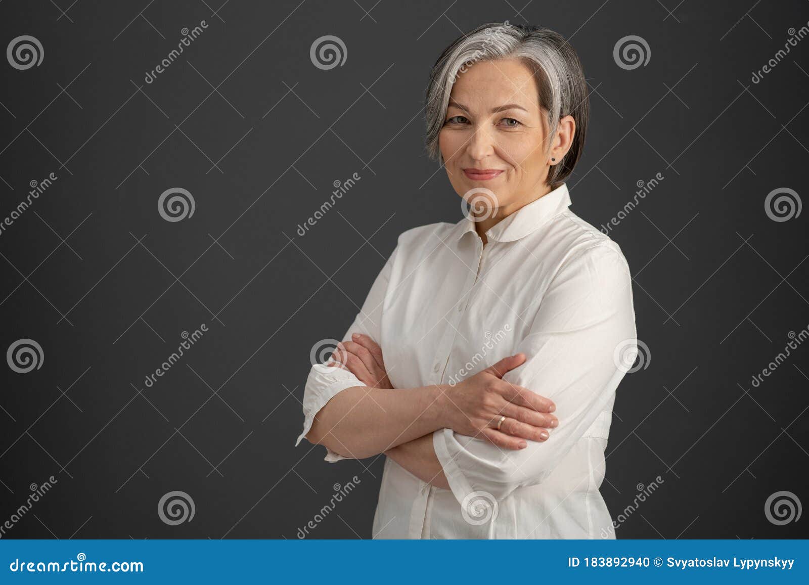 intelligent silver-haired woman smiles with arms crossed. pretty business woman looking at camera confidently. 