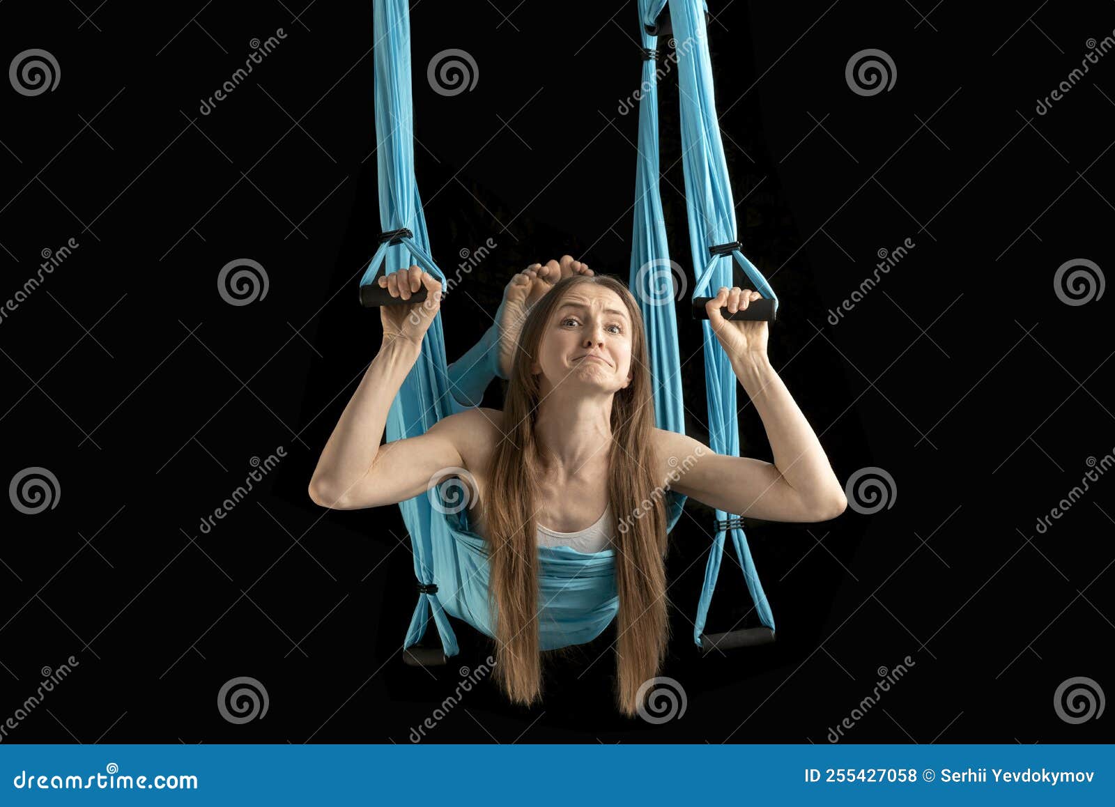 Exercising woman holding gymnast rings and looking away. Female