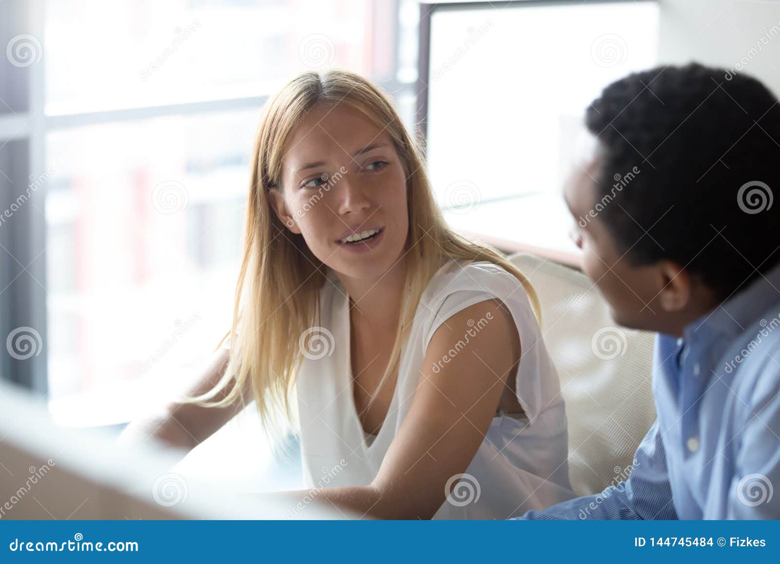 young caucasian businesswoman manager listening to african colleague having discussion
