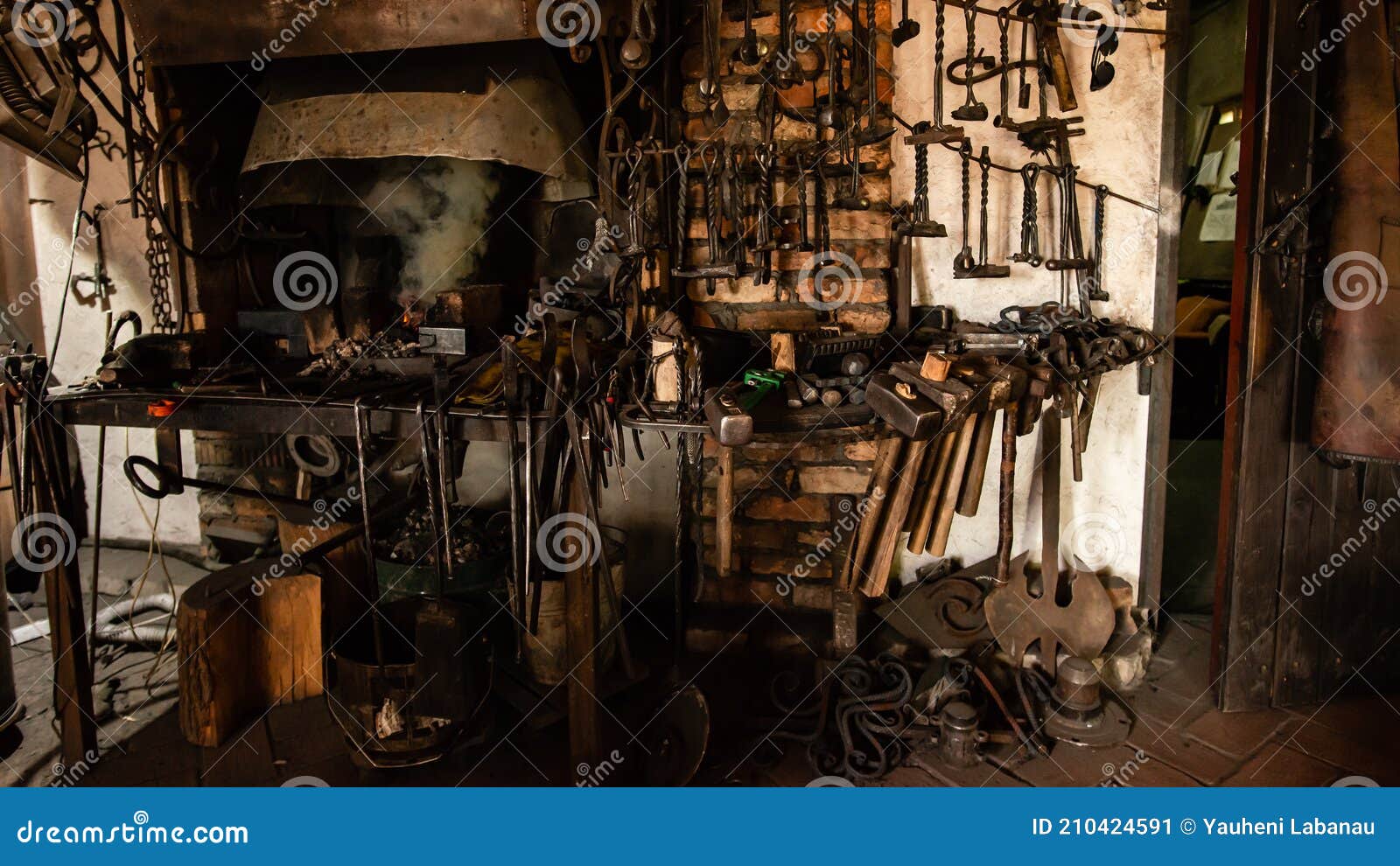 interior of blacksmith forge with tools hanging on wall and anvil and hammer ready to be used. furnace formant